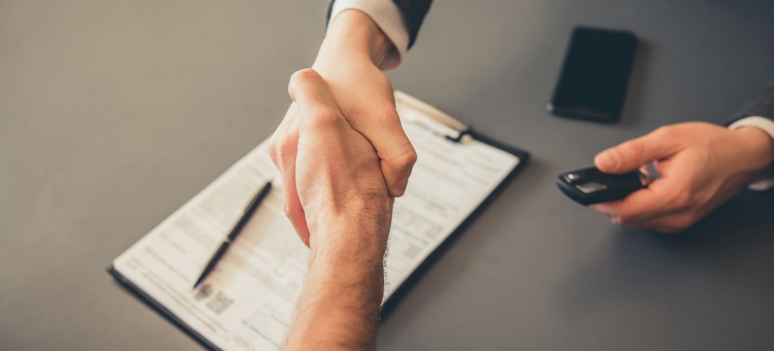 Geschäftliche Verhandlung mit Handschlag und Dokumenten.